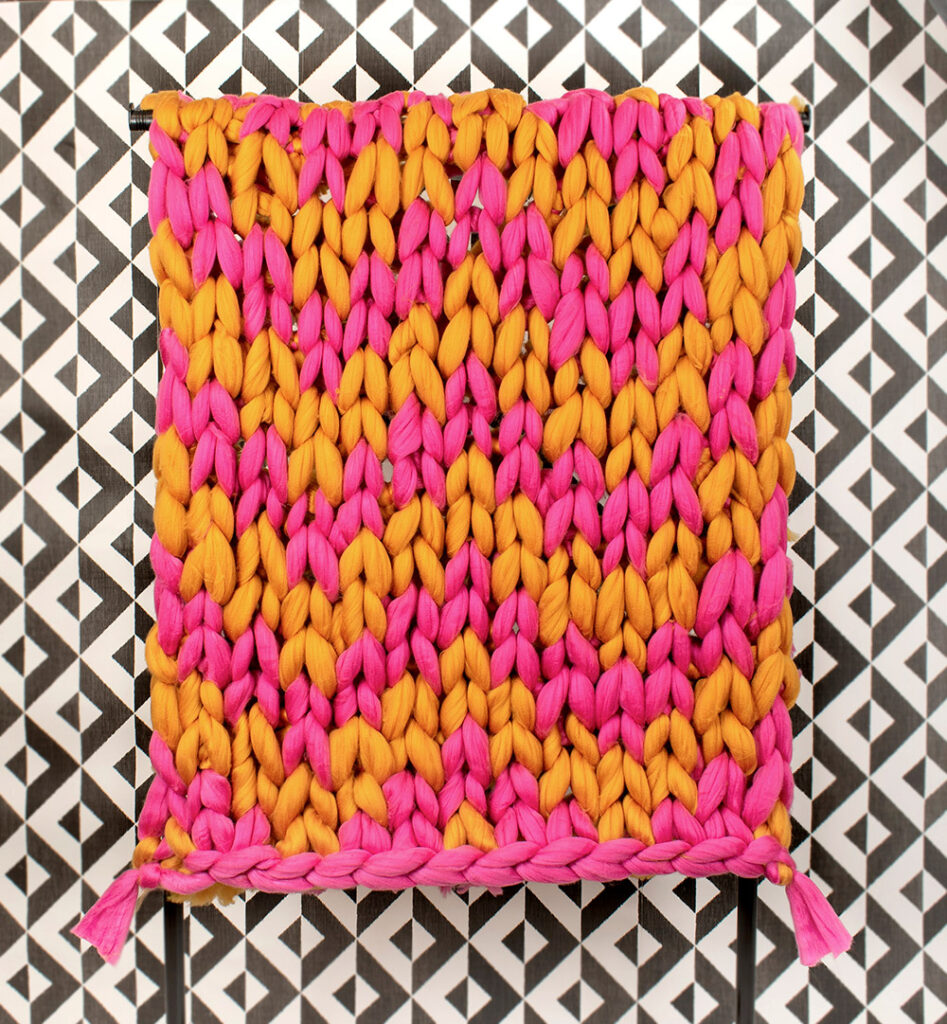 arm knitted blanket pattern, chevron arm knit blanket made using bright pink and mustard Mammoth yarn